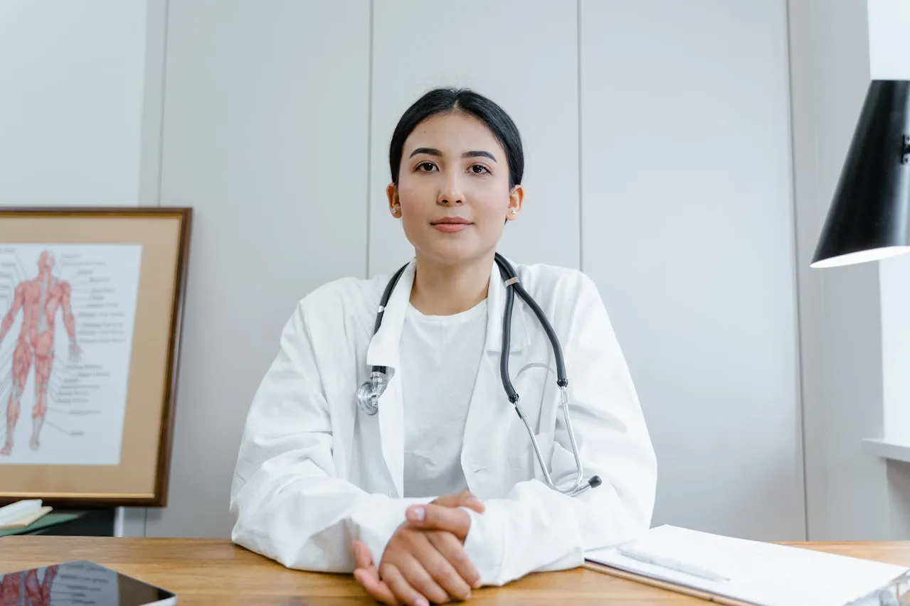 A doctor in a white coat, wearing a stethoscope.